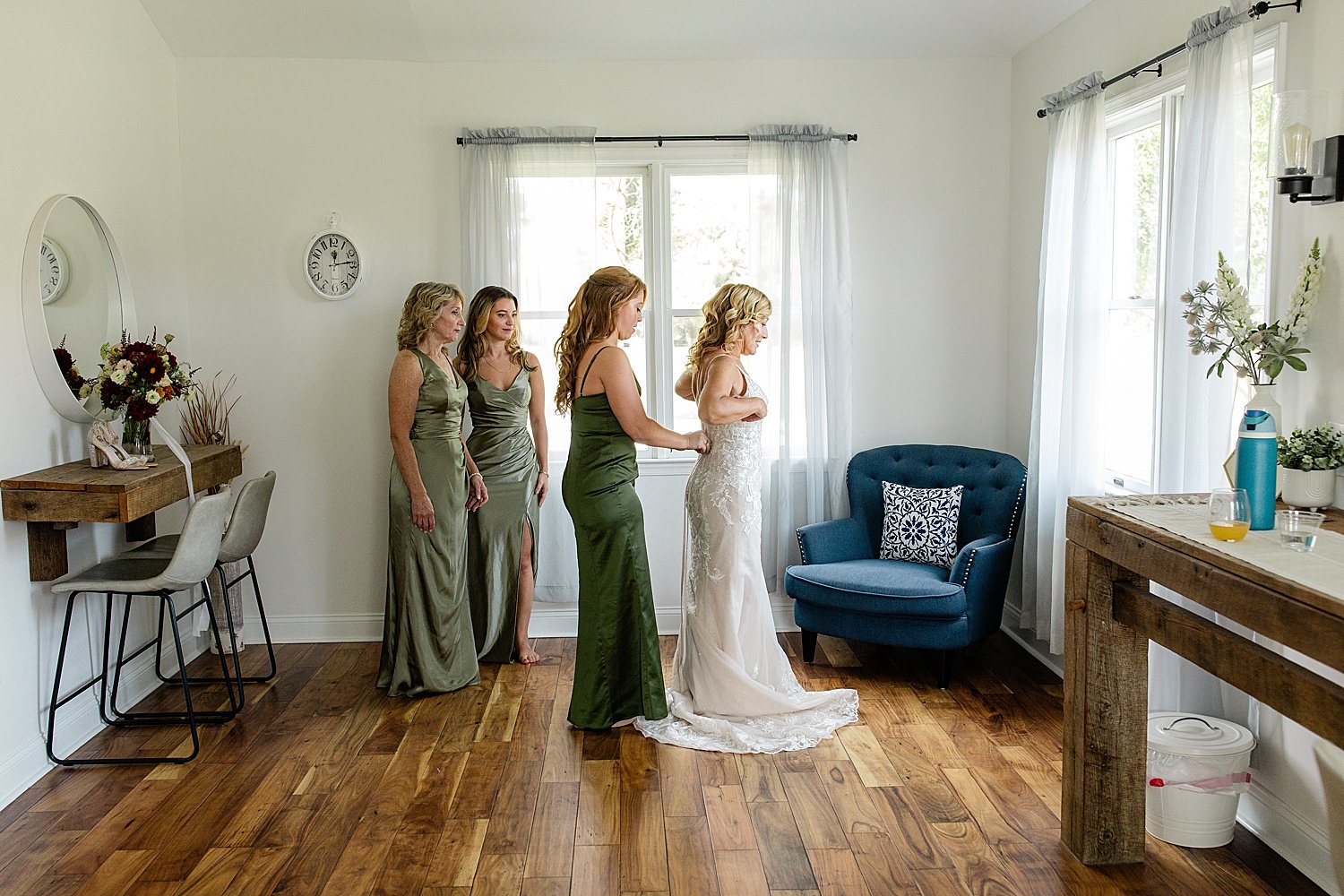 Woman gets bridal gown adjusted before ceremony by Jen Harvey Photography