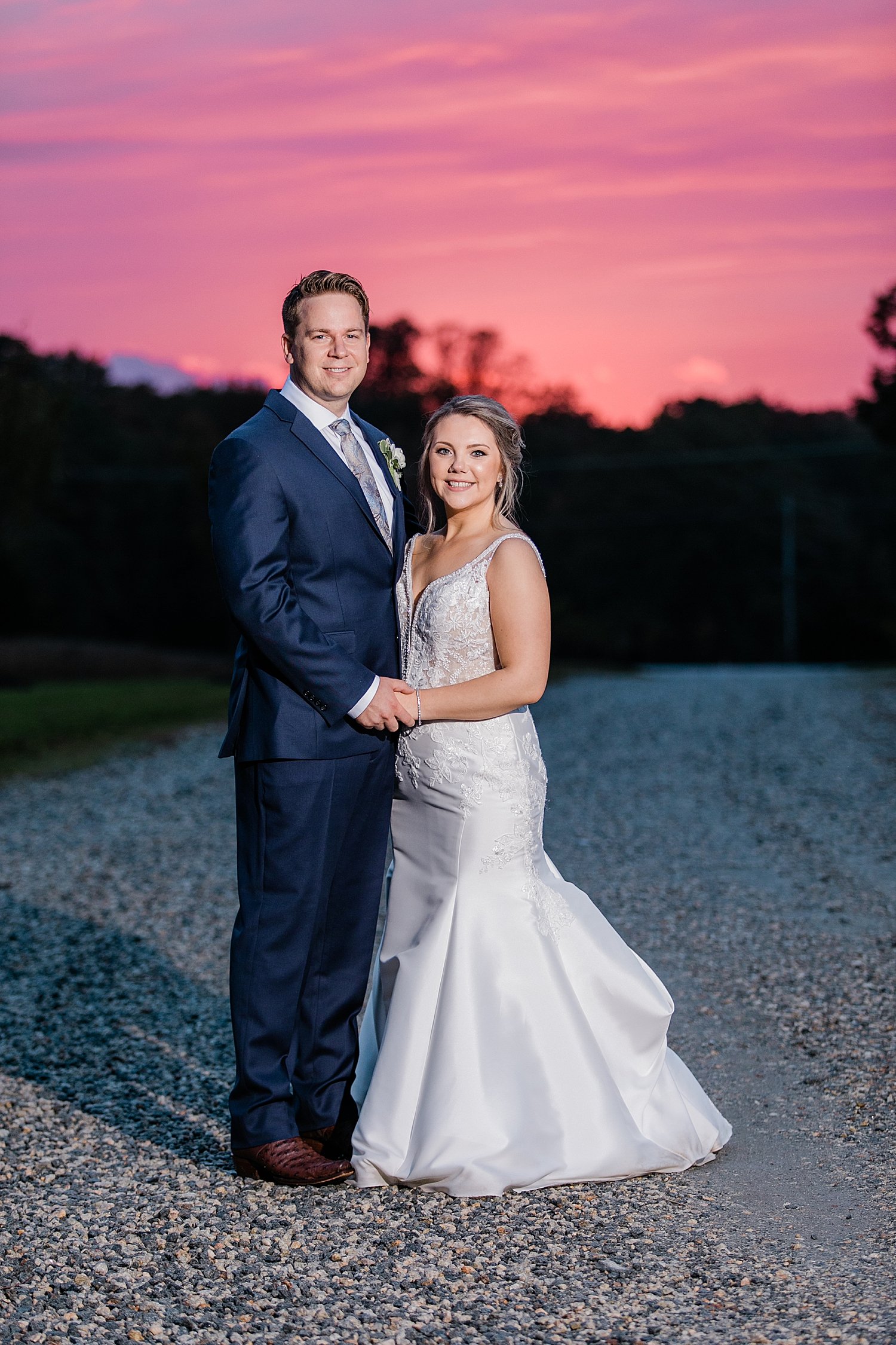 couple standing on gravel road during pink sunset by Baltimore wedding photographer
